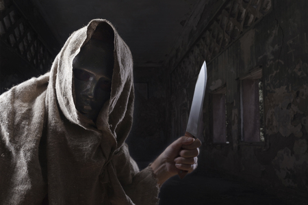 Man in iron mask with a big knife in his hand in a abandoned house ,  Halloween concept.の写真素材