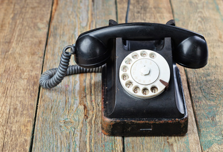 Old black phone on a wooden table.の写真素材