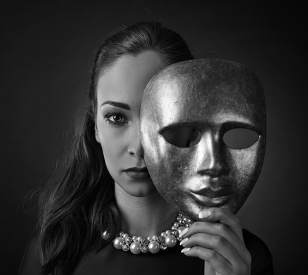 Beautiful woman in black dress with mask, perfect make-up and hair.の写真素材