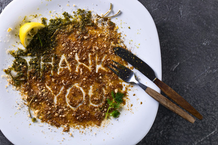 Dirty plate and Cutlery on the table after lunch . The view from the top .The words thank you .