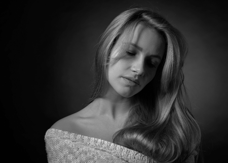 Portrait of a young attractive blonde without makeup with long curly hair . Black background .の写真素材