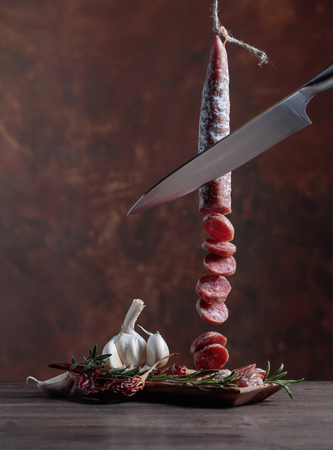 Homemade smoked salami with rosemary, garlic and pepper on a old wooden table.の写真素材