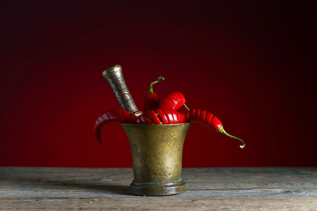 Red chili pepper in old copper mortar on a black backgroundの写真素材
