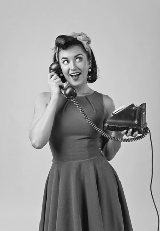 Beautiful woman in retro style with perfect hair and make up , speaking via vintage phone.の写真素材