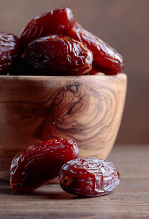 Juicy dates in a bowl on a old wooden table .の写真素材