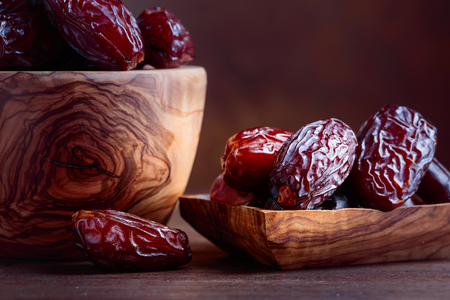 Juicy dates in a bowl on a old wooden table .