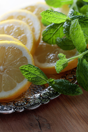 Lemon slices with mint leaves in old silver dish on a wooden table.の写真素材