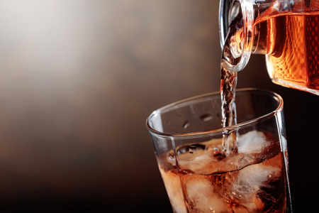 Whiskey is poured from a carafe into a glass with ice.Copy space.の写真素材