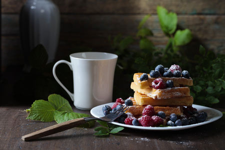  Yummy sweet waffles with raspberry and blueberry on a old wooden table .の写真素材