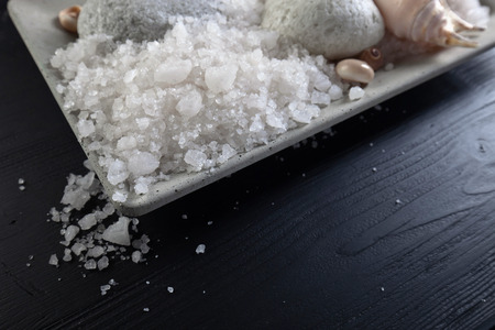 Sea salt  with stones and shells on white wooden table. Copy space.の写真素材