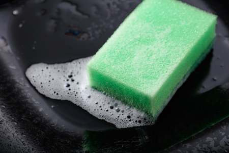 Wet black dish and sponge with detergent .の写真素材