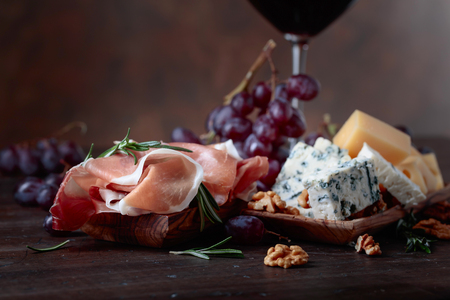 Prosciutto with various cheeses , grapes and  walnuts on a old wooden table.の写真素材