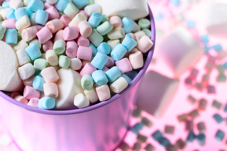 Violet pail with various marshmallows on a pink background.の写真素材