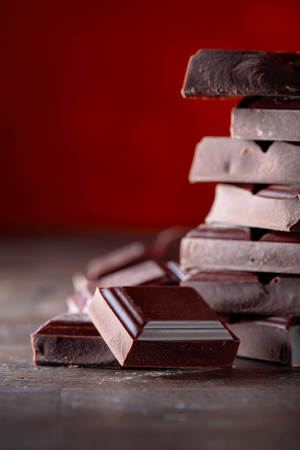 Broken black chocolate pieces on a wooden background. Copy space.の写真素材