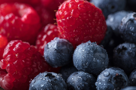  Ripe and juicy fresh picked berries closeup. Blueberries and raspberries background.