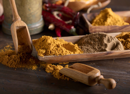 Various Indian spices with wooden spoons on a old wooden table.の写真素材