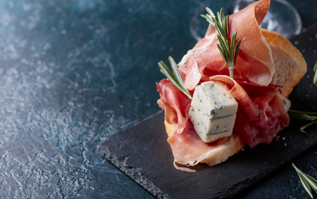 Sandwich with prosciutto, blue cheese and rosemary on a dark background.  Copy space for your text.の写真素材