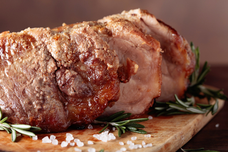 Oven-baked pork with rosemary and spices on a old wooden table.の写真素材