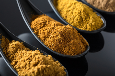 Small black bowls of Indian spices on black reflective background .の写真素材