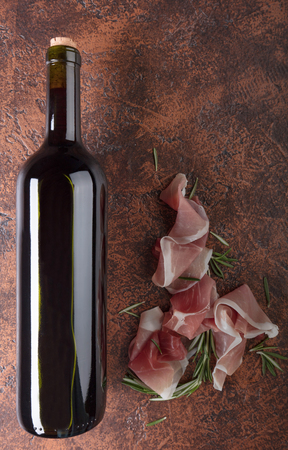 Prosciutto with rosemary and bottle of red wine. Top view, copy space.の写真素材