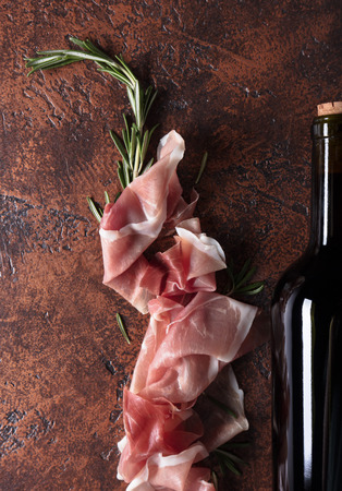 Prosciutto with rosemary and bottle of red wine. Top view, copy space.の写真素材