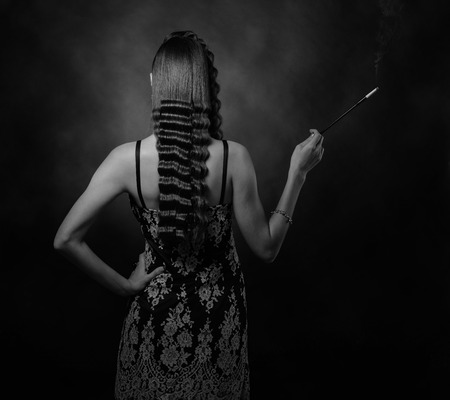 Beautiful woman with perfect long hair and makeup . Attractive girl with long mouthpiece on a black background . Studio shot .の写真素材