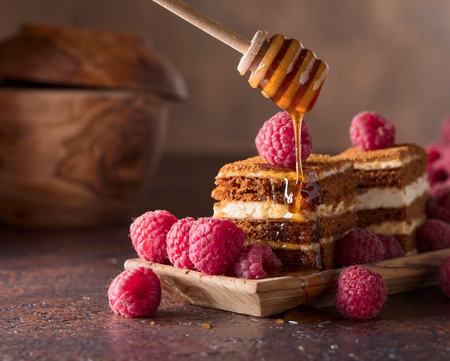 Homemade layered honey cake with cream and red raspberries.の写真素材