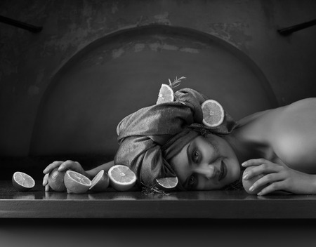 Young woman in green turban with lemons , limes and rosemary on dark background . Copy space for your text .の写真素材