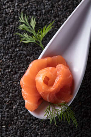 Slice of salted salmon with dill on the background of black sesame. Top view.の写真素材