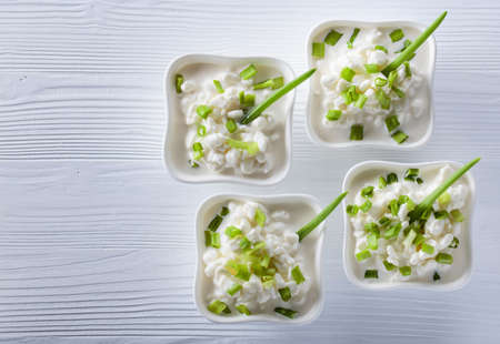 Homemade cottage cheese with green onions on white wooden table. Top view , copy space.