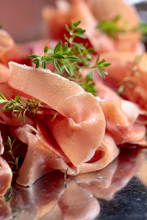 Italian prosciutto crudo or jamon with thyme on a metal platter .の写真素材