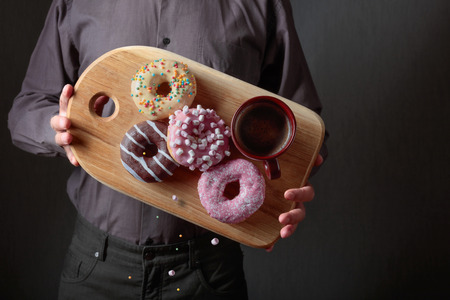 Man with various sweet donuts on a dark background.の写真素材