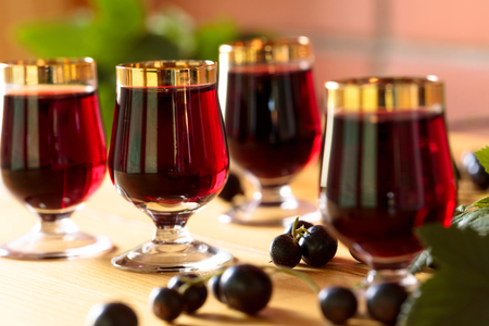 Homemade black currant liqueur and fresh berries, wooden background.の写真素材