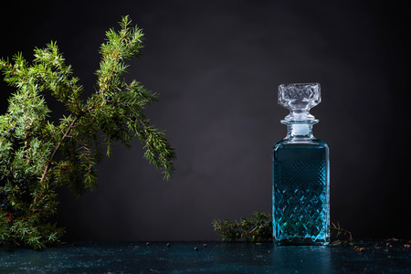 Blue gin in crystal decanter and juniper branch with berries on a black background. Copy space for your text.の写真素材