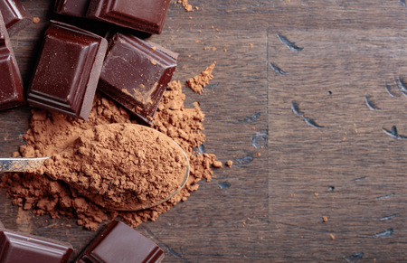 Broken  chocolate pieces and cocoa powder in small spoon on a wooden background.Top view , copy space.の写真素材