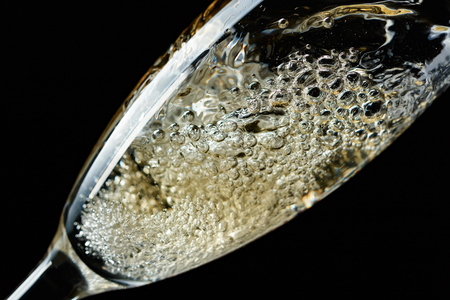 Glass of splashing champagne isolated on black background.の写真素材