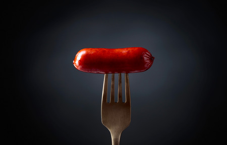 Grilled sausage on a fork. Black background, copy space.の写真素材