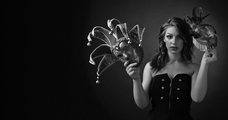 Attractive woman with long curly hair holding in hand carnival mask. Black and white. Copy space.の写真素材