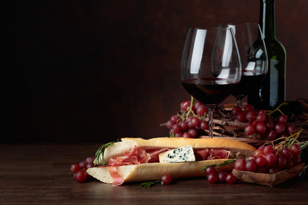 Sandwich with prosciutto, blue cheese and rosemary on a dark background. Delicious snack and red wine. Copy space for your text.の写真素材