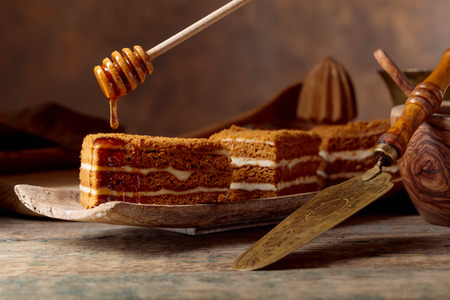Homemade layered honey cake with cream on a old wooden table.の写真素材