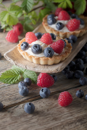 Dessert tarts with raspberries and blueberries on a old wooden table.の写真素材