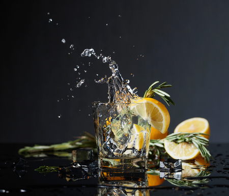 Cocktail gin-tonic with lemon slices and twigs of rosemary. Lemon slice falls into the glass. Copy space.の写真素材