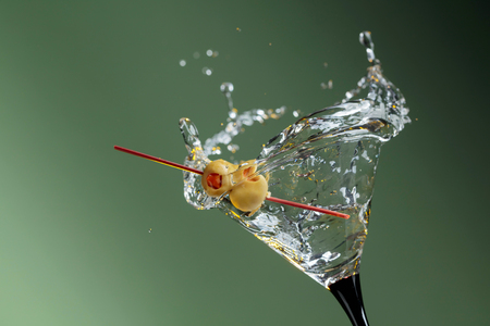 Dry martini with green olives. Cocktail in glass with splashes. Mixed light. Copy space for your text.の写真素材