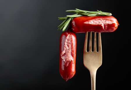 Grilled sausages with rosemary. Black background, copy space.