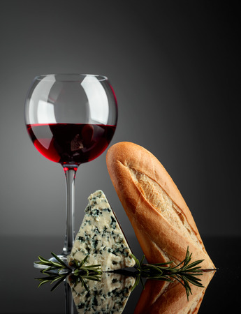 Blue cheese with bread, rosemary and red wine on a black reflective background. Copy space for your text.の写真素材