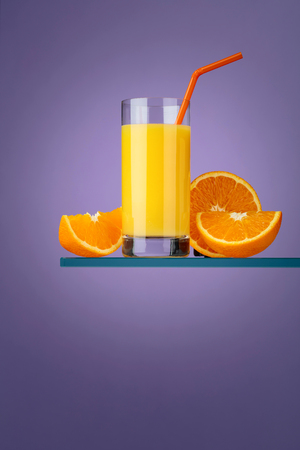 Glass of fresh orange juice with fresh fruits on a purple background. Copy space.の写真素材