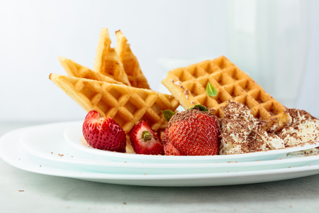 Belgian waffles with strawberries and cream, decorated with fresh mint and sprinkled with chocolate chips.の写真素材