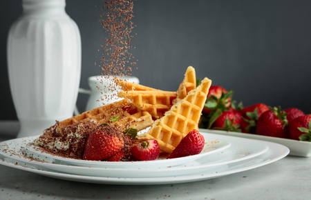 Belgian waffles with strawberries and cream, decorated with fresh mint and sprinkled with chocolate chips.の写真素材
