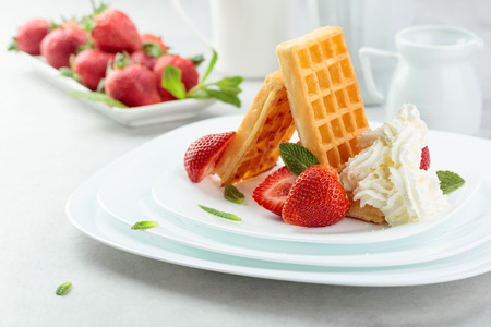 Belgian waffles with strawberries and cream garnished with fresh mint.の写真素材