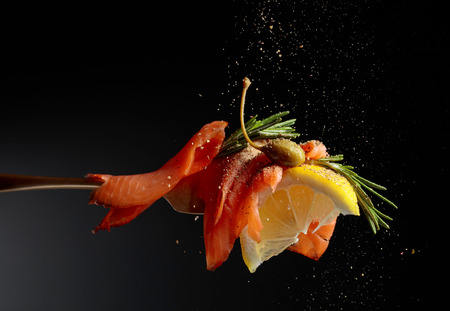 Trout fillet, lemon slice, capers and rosemary sprinkle with pepper. Black background, copy space.の写真素材